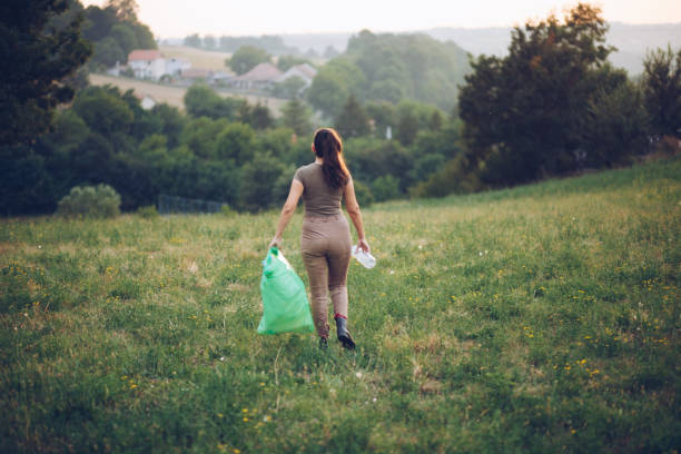 istock Female volunteer picks up trash in park 1164839311