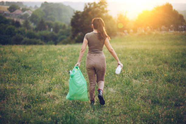 istock Female volunteer picks up trash in park 1164839962