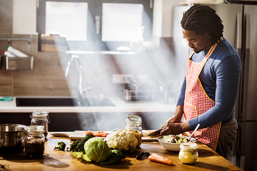 Young black man chopping vegetables while preparing food in the kitchen. Copy space.