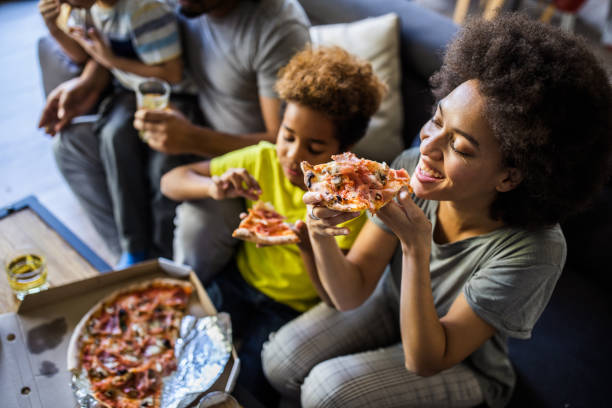 szczęśliwa czarna rodzina o pizzy na lunch w domu. - pizza eating african descent lunch zdjęcia i obrazy z banku zdjęć