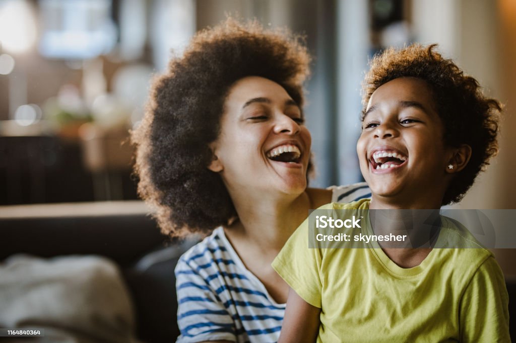 Cheerful African American mother and daughter at home. Cheerful black mother and daughter having fun while laughing at home. Laughing Stock Photo