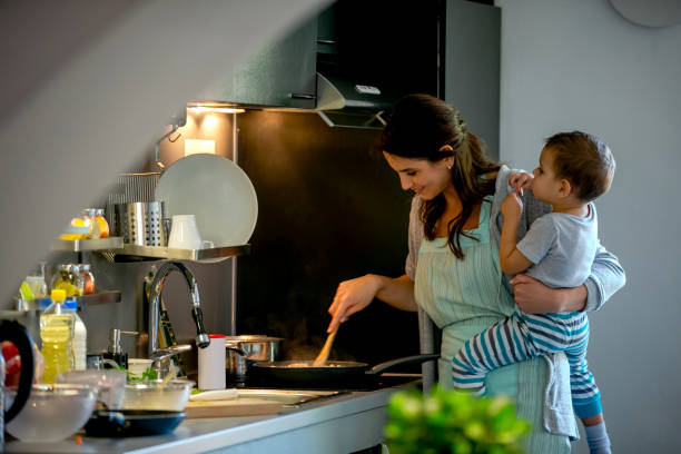 istock Stirring meal in the pan with her toddler on hip 1164841265