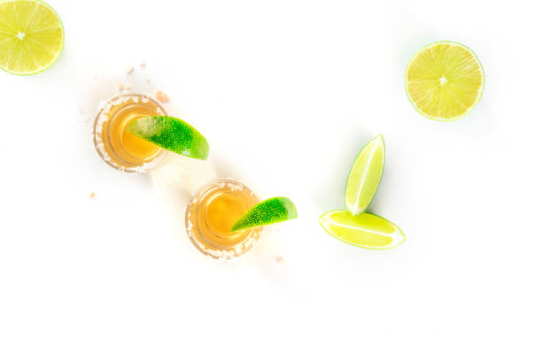 Golden tequila with lime slices on white, top shot Golden tequila with lime slices on a white background, top shot with a place for text tequila shot stock pictures, royalty-free photos & images
