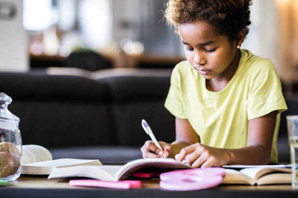 istock African American girl doing her homework at home. 1164841635
