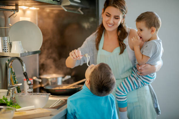 istock Giving her son spaghetti on fork to taste, holding toddler 1164841705