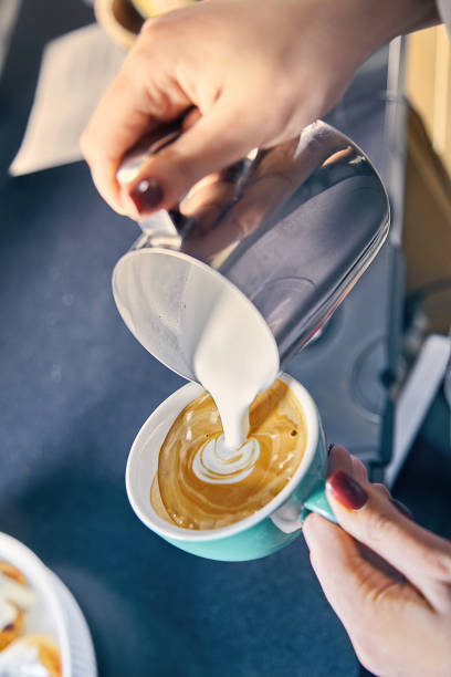 professional service at cafe concept. coffee house. Barista Making of cafe latte art. pouring milk in glass of fresh made coffee. Milk and coffee toned picture. Hand of Barista making latte or cappuccino