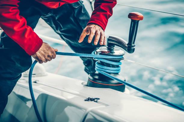 Sailor winding rope on winch with hands Sailor winding rope of foresail on winch with hands before rotating handle. Model released. Taken by Sony a7R II, 42 Mpix. yachting stock pictures, royalty-free photos & images