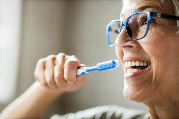 close up of happy senior woman brushing her teeth. - brushing teeth women toothbrush brushing imagens e fotografias de stock