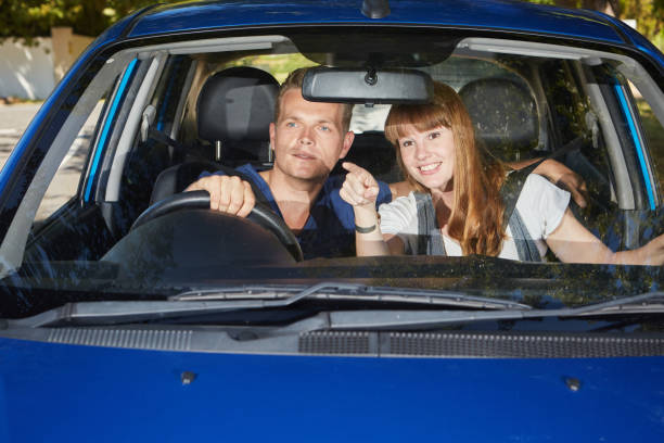 istock Young couple in car smilingly point at something 1164850937