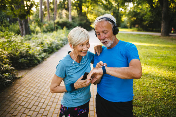 pares sênior que usam o relógio esperto ao exercitar ao ar livre - senior couple audio - fotografias e filmes do acervo