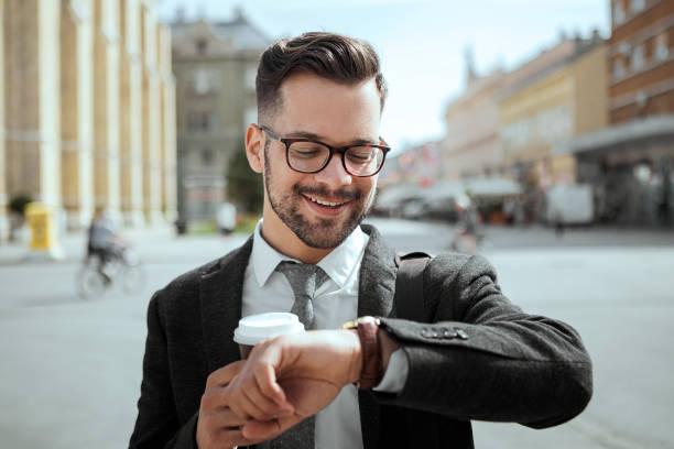 istock Businessman looking at watch holding coffee cup 1164858773