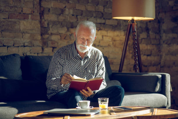 Senior man enjoying reading a book indoors