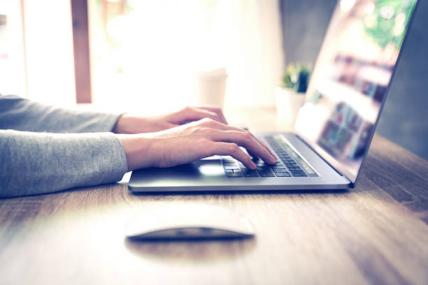 istock asian woman using laptop computer do online activity on wood table at home office. 1164862098