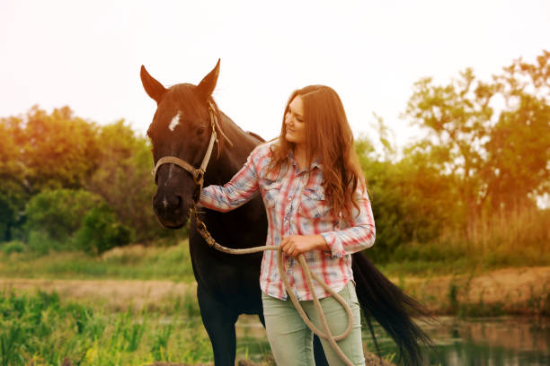 istock brunette young woman standing outdoors with her black horse 1164862366