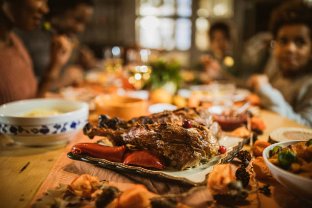 Close up of roasted turkey legs on a tray with people in the background.
