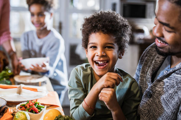 istock Cheerful black boy with his father at dining table. 1164865734