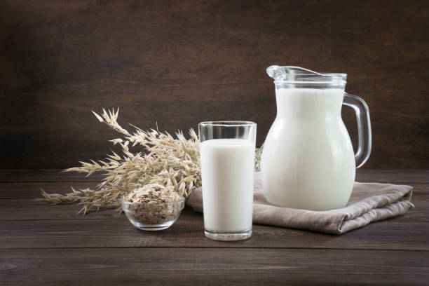 istock Fresh oat milk in glass and pitcher on dark wooden table. Rustic style. 1164868145