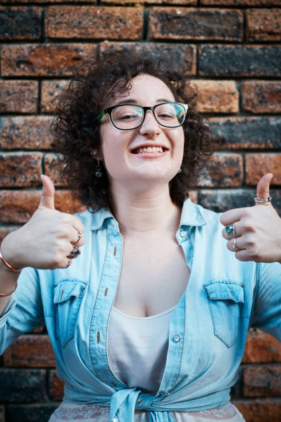 istock Double thumbs-up signals from cheerfully smiling young brunette 1164868891