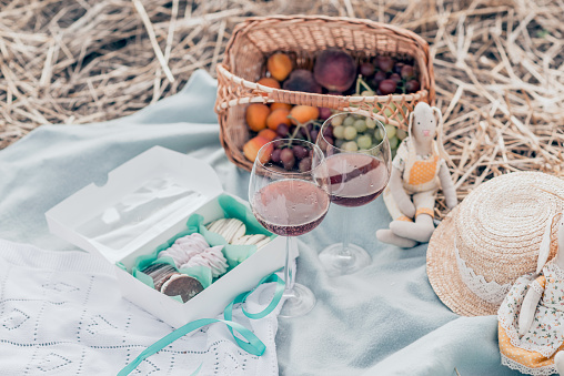 Two glasses of red wine, fruits and sweets on the sunset picnic. Top view.