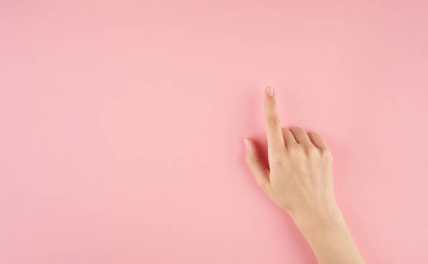 istock Beautiful woman hand touching or pointing on something on pink background with copy space top view 1164870810