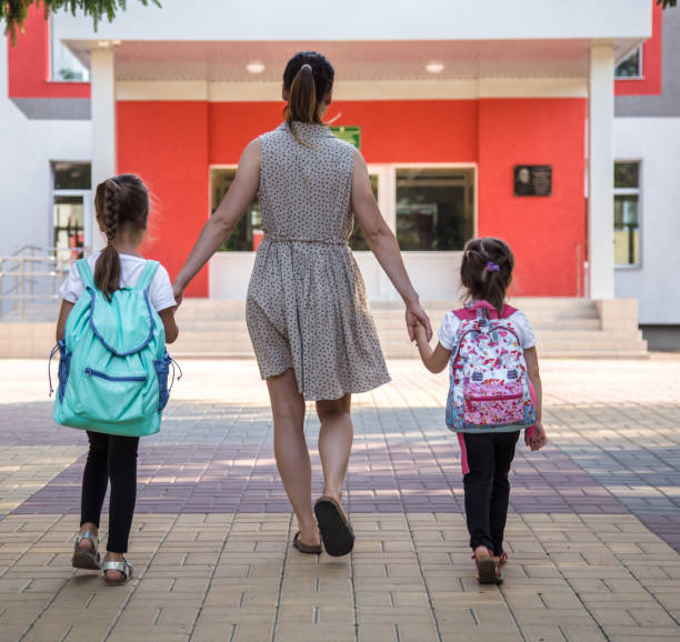 istock Back to school education concept with girl kids, elementary students, carrying backpacks going to class 1164873248