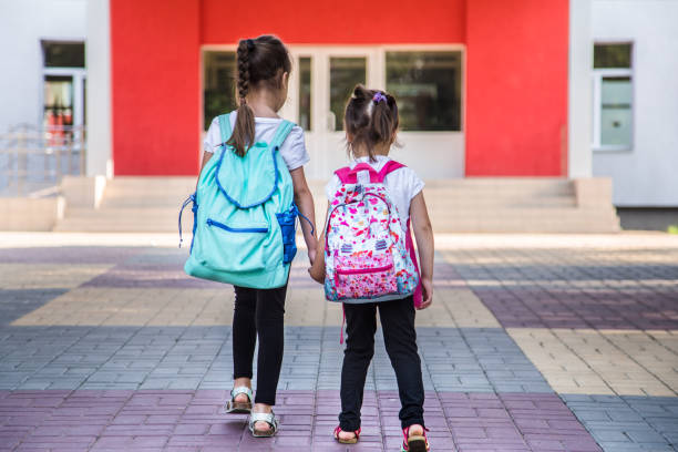istock Back to school education concept with girl kids, elementary students, carrying backpacks going to class 1164873256