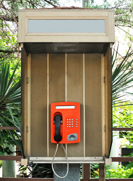Red vintage payphone for phone cards in public telephone box outdoors