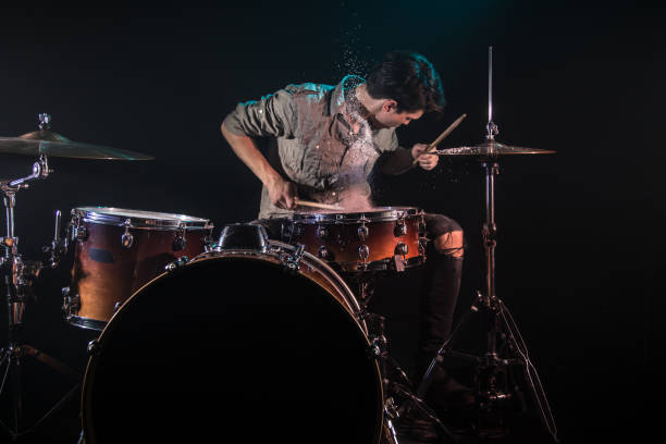 musician playing drums with splashes, black background with beautiful soft light musician playing drums with splashes, black background with beautiful soft light, emotional play, music concept rhythm photos stock pictures, royalty-free photos & images