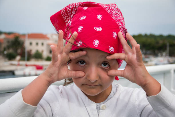 Little girl with a red headscarf. I'm watching you! Little girl with a red headscarf enjoy traveling by ferry. ferry deck girls stock pictures, royalty-free photos & images