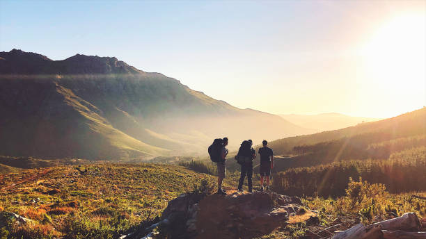 задний вид туристов с рюкзаками, наслаждаясь закатом в горах - mountain hiker стоковые фото и изображения