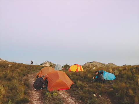 A group of tents on top of a mountain in the wilderness with hikers gathering breakfast and making coffee above Stellenbosch Cape Town South Africa