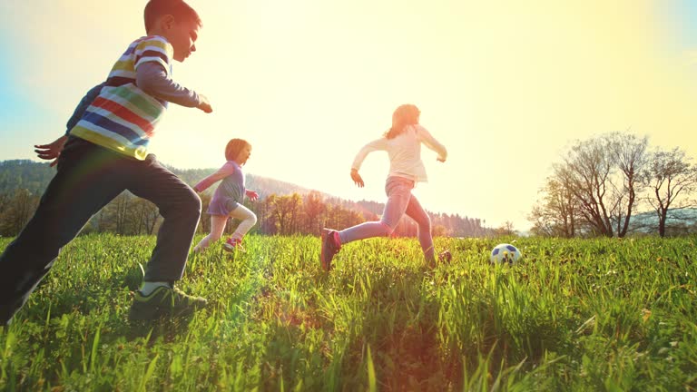 SLO MO TS Children playing football in a sunny meadow