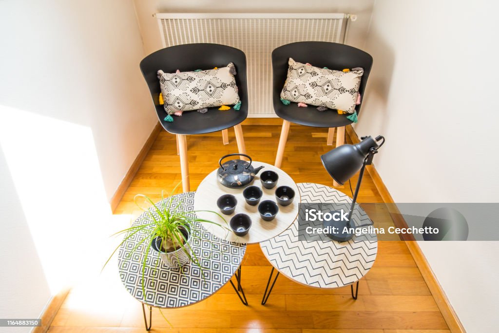 Stylish Interior Decoration of a Cosy Corner of a House with Cast Iron Teapot, Cups, Geometric Tables and Chairs Alcove Stock Photo