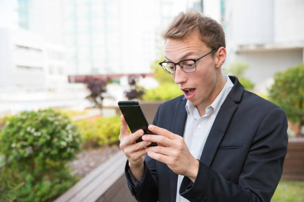 istock Excited office employee with cellphone getting shocking news 1164884430