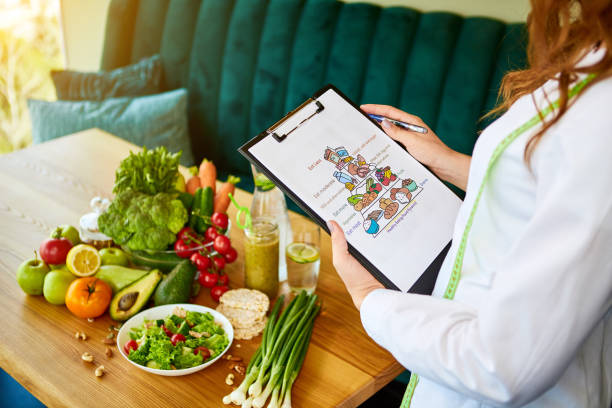 istock Holding schematic meal plan for diet with various healthy products on the background. Weight loss and right nutrition concept. Eating food pyramid 1164885313