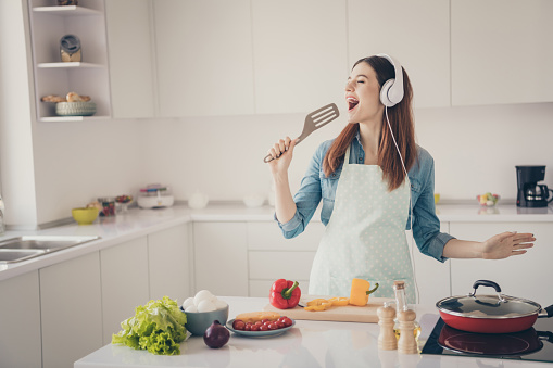 Photo of wife begin prepare family dinner singing like rock star with kitchenware utensil overjoyed earflaps playlist