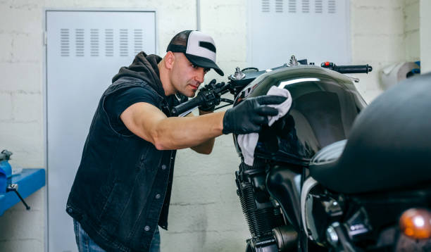 Mechanic cleaning a motorcycle Mechanic cleaning a customized motorcycle in his workshop super bike stock pictures, royalty-free photos & images