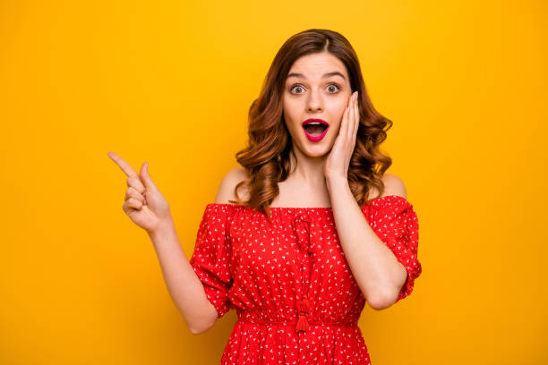 Pretty lady indicating fingers empty space showing black friday prices wear red dress isolated yellow background Pretty lady indicating fingers, empty space showing black friday prices wear red dress isolated yellow background woman in red dress stock pictures, royalty-free photos & images