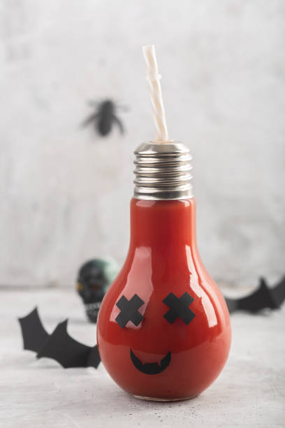灰色の背景に怖い顔とガラス瓶のハロウィーン健康トマトジュース - glass autumn halloween food ストックフォトと画像