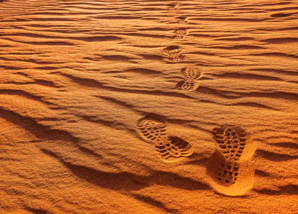 Photo of traces of shoes on golden sand in desert