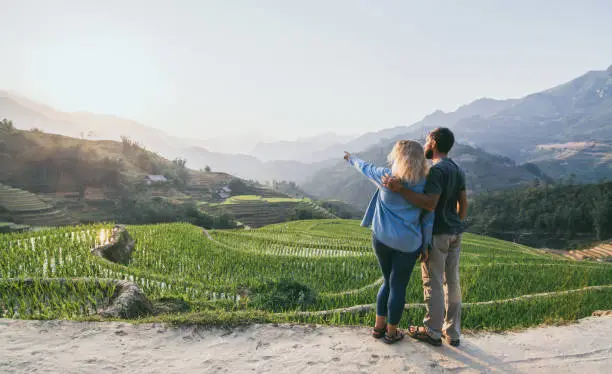 Photo of Young Caucasian couple overlooking rice terraces of Sapa at sunset in Lao Cai region of Vietnam