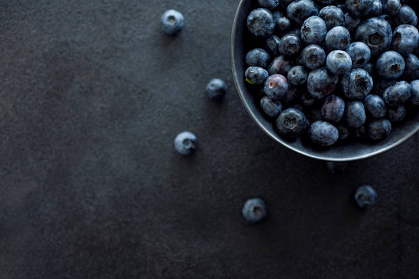 istock Fresh blueberries in a dark ceramic bowl on a black background, top view 1164895598