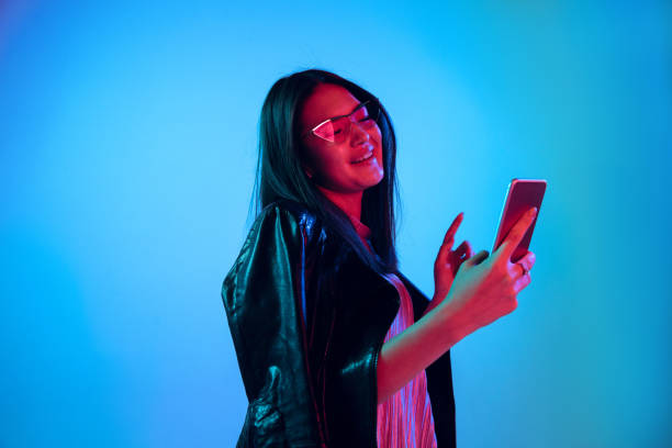 istock Beautiful girl's facial expression in neon light on blue studio background 1164899668