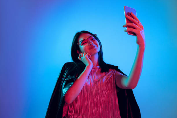 istock Beautiful girl's facial expression in neon light on blue studio background 1164899670