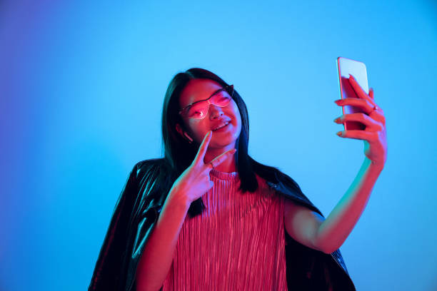 istock Beautiful girl's facial expression in neon light on blue studio background 1164899672