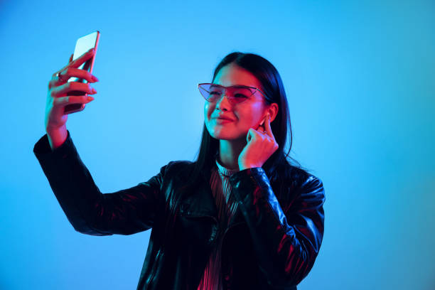 istock Beautiful girl's facial expression in neon light on blue studio background 1164899676