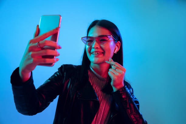 istock Beautiful girl's facial expression in neon light on blue studio background 1164899678