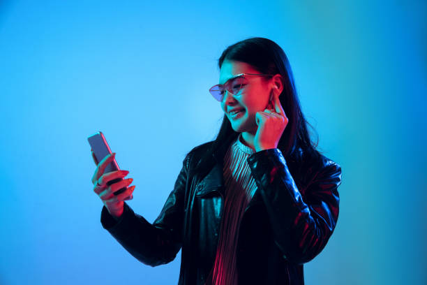 istock Beautiful girl's facial expression in neon light on blue studio background 1164899679