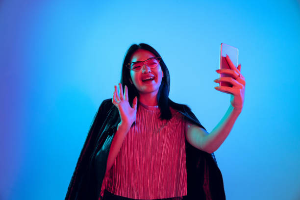 istock Beautiful girl's facial expression in neon light on blue studio background 1164899680
