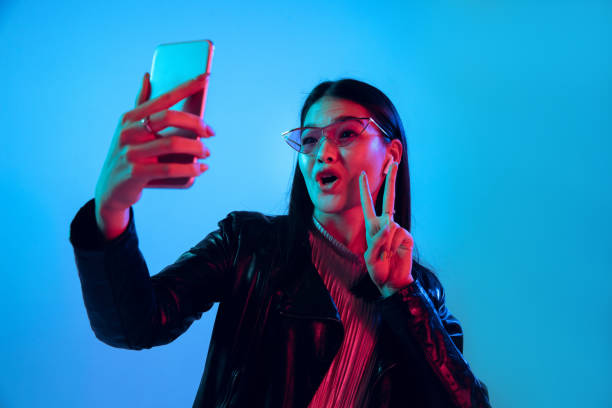Beautiful girl's facial expression in neon light on blue studio background